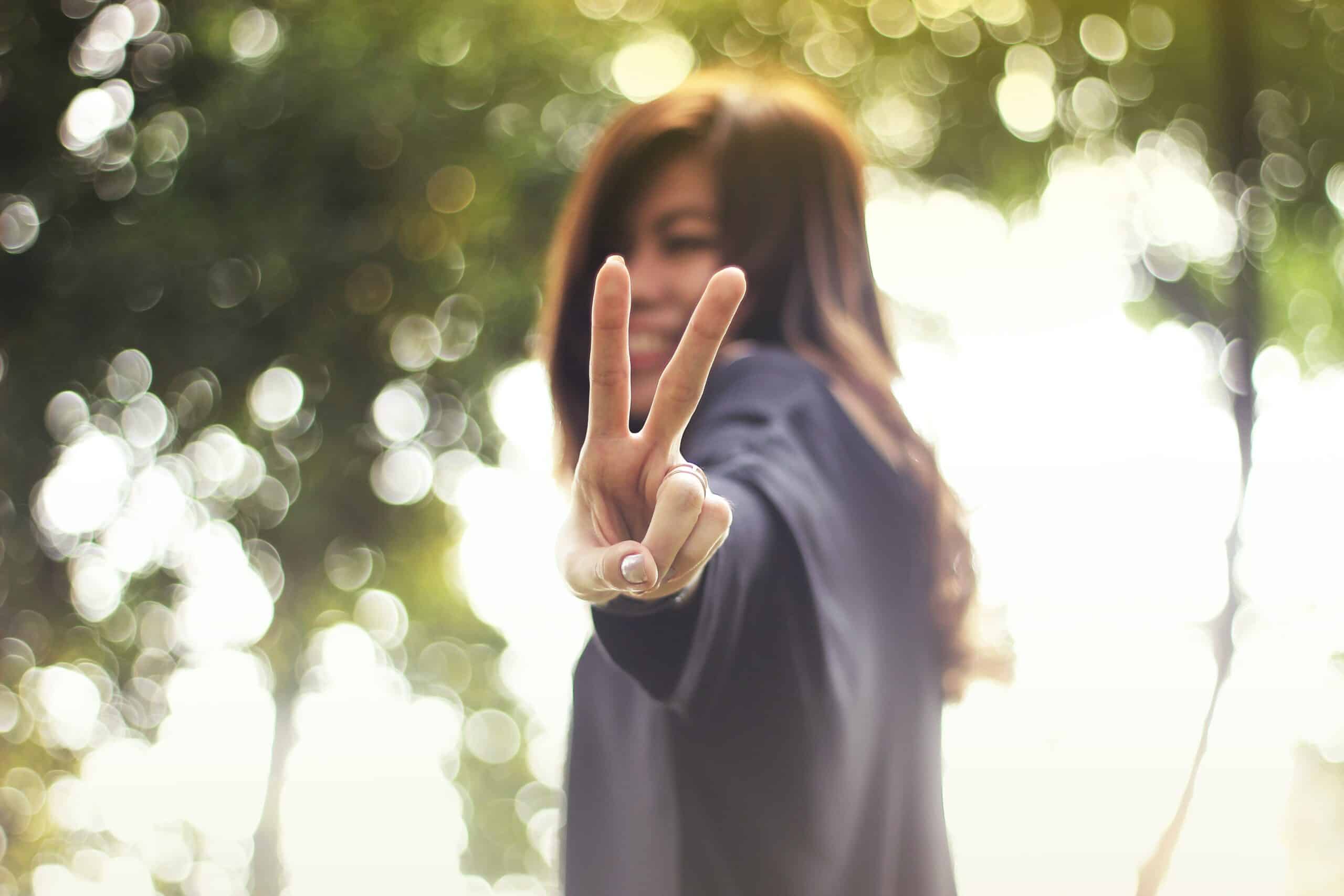 Woman flashes peace sign | Photo by Miguel Constantin Montes