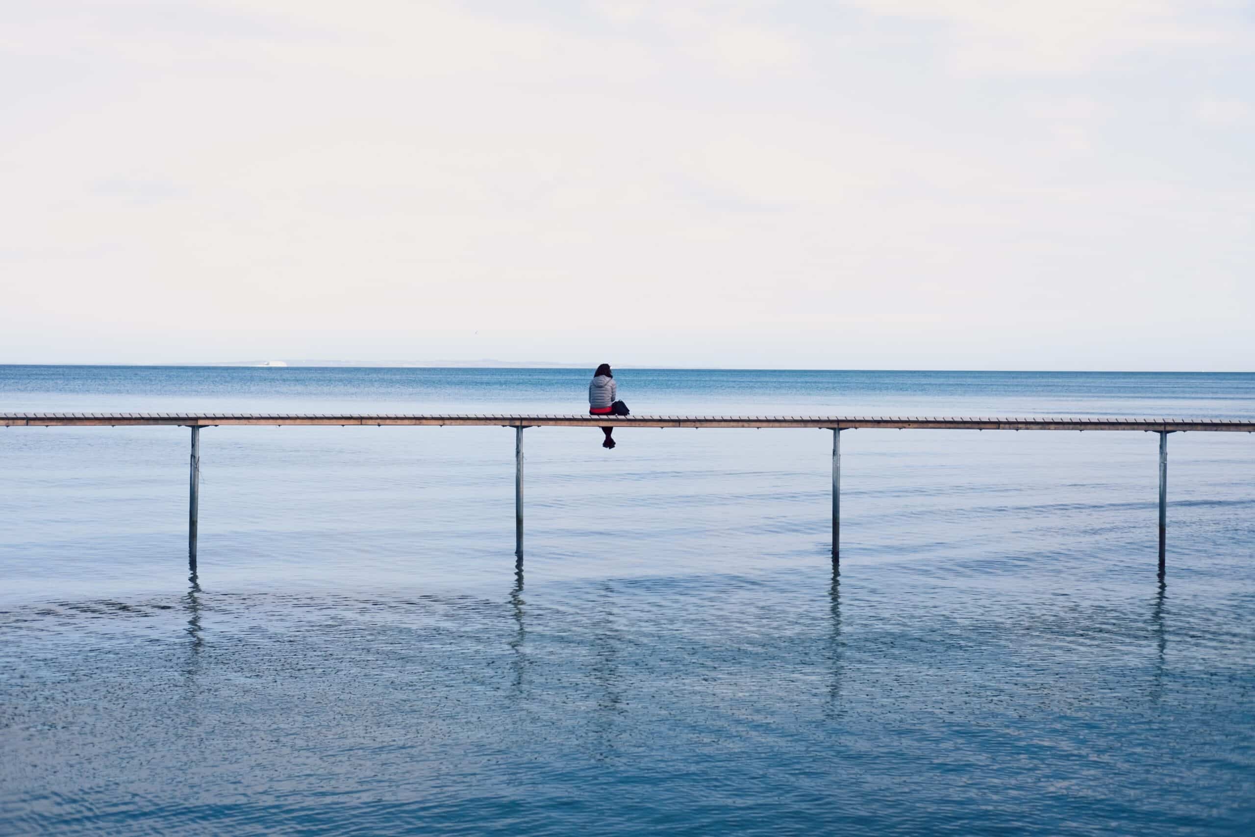 woman sitting alone | Photo by Thomas Peham on Unsplash