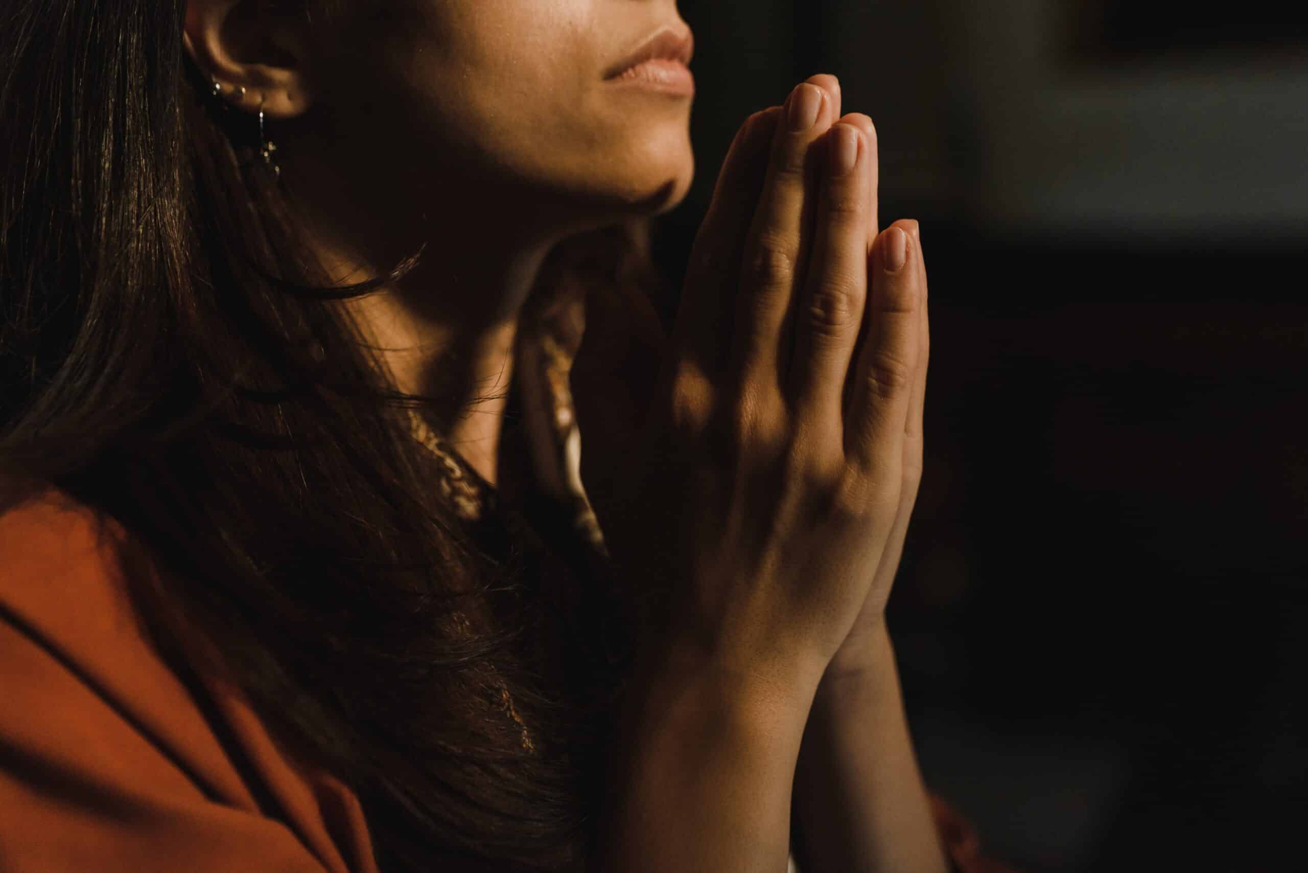 Woman praying | Photo by Arina Krasnikova: https://www.pexels.com/photo/a-person-in-orange-shirt-with-hands-together