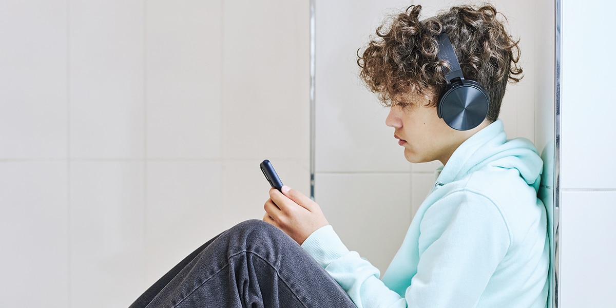 young boy with headphones sitting by himself