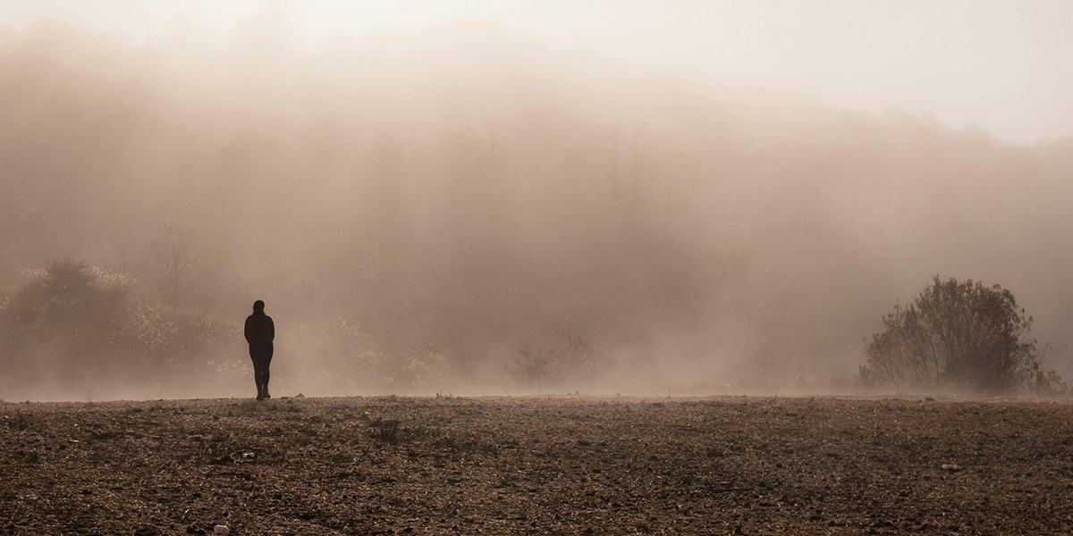 man walking in a field alone