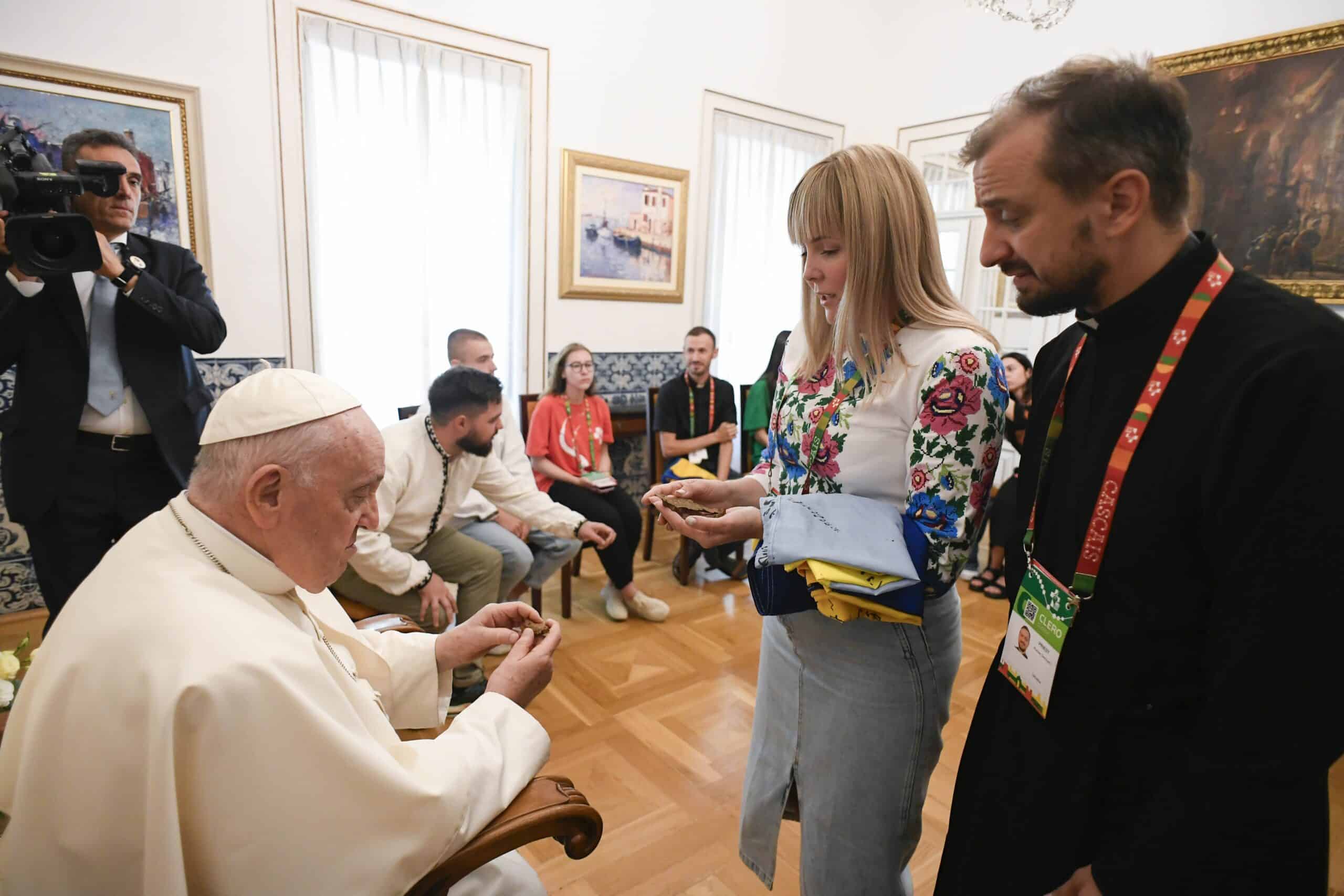 A young woman and a priest from Ukraine give Pope Francis shards from their war-torn country during a private meeting Aug. 3, 2023, at the Vatican nunciature in Lisbon, Portugal. The Vatican said the pope spent half an hour with a group of Ukrainian pilgrims attending World Youth Day, listening to their stories and praying for peace. (CNS photo/Vatican Media)