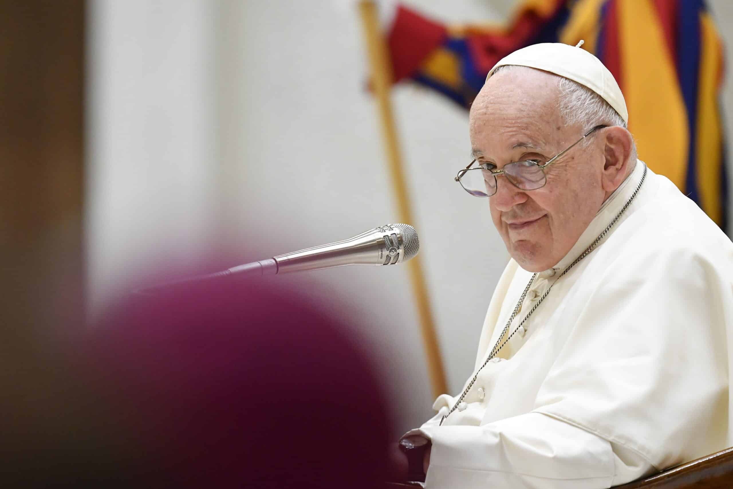 Pope Francis smiles at a bishop during his weekly general audience