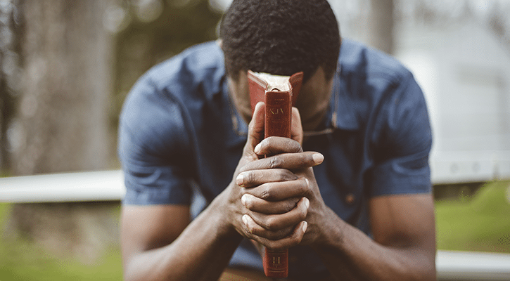 man praying on a park bench