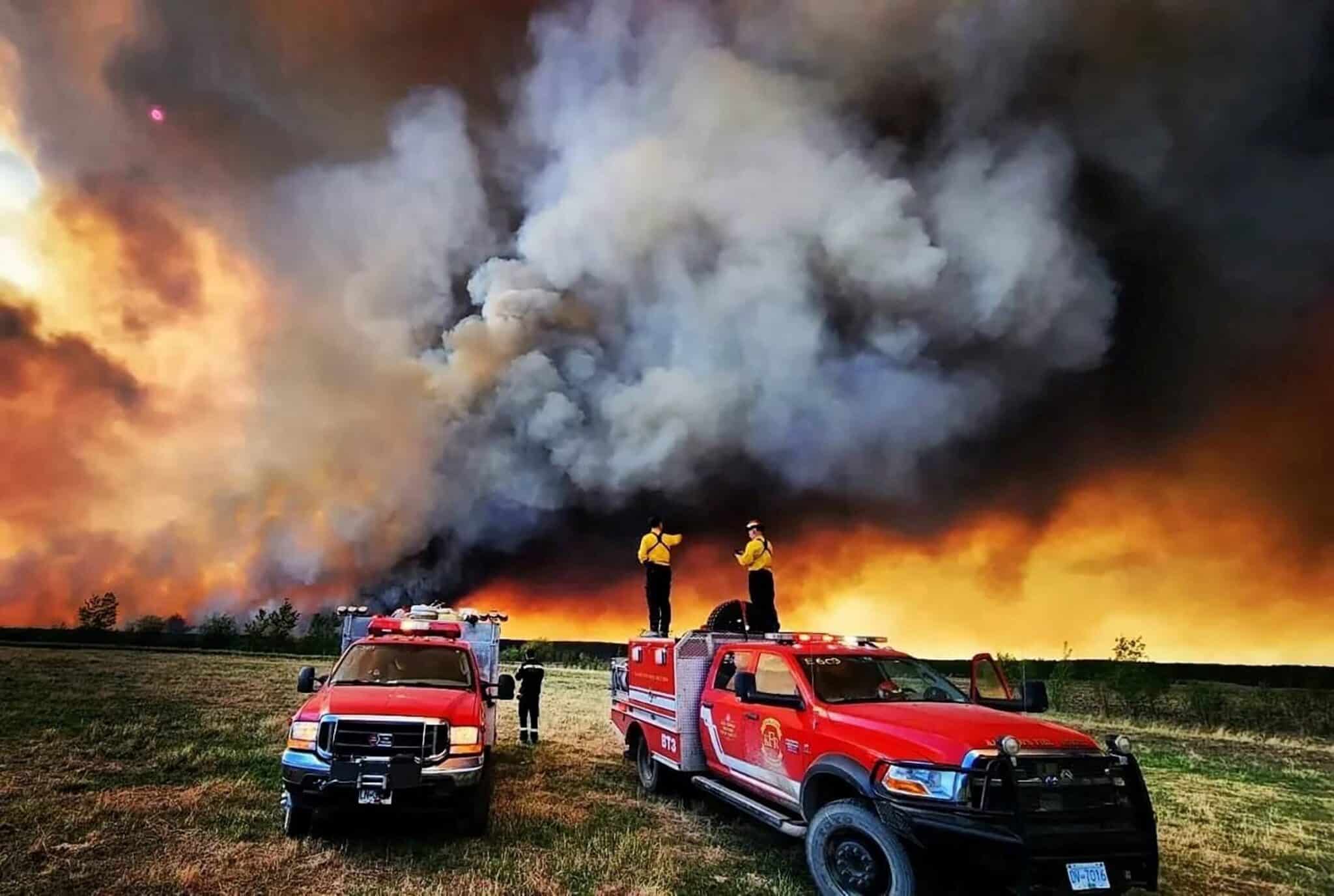 Firefighters stand on a Kamloops Fire Rescue truck at a wildfire near Fort St. John, British Columbia, May 14, 2023. Wildfires have always occurred, but experts say the warming climate is increasing their severity. (OSV News photo/Kamloops Fire Rescue handout via Reuters)