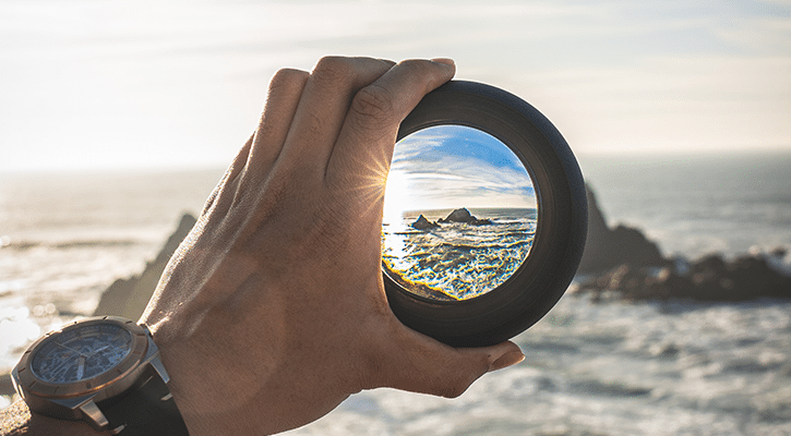 hand holding photo lens that is in focus.