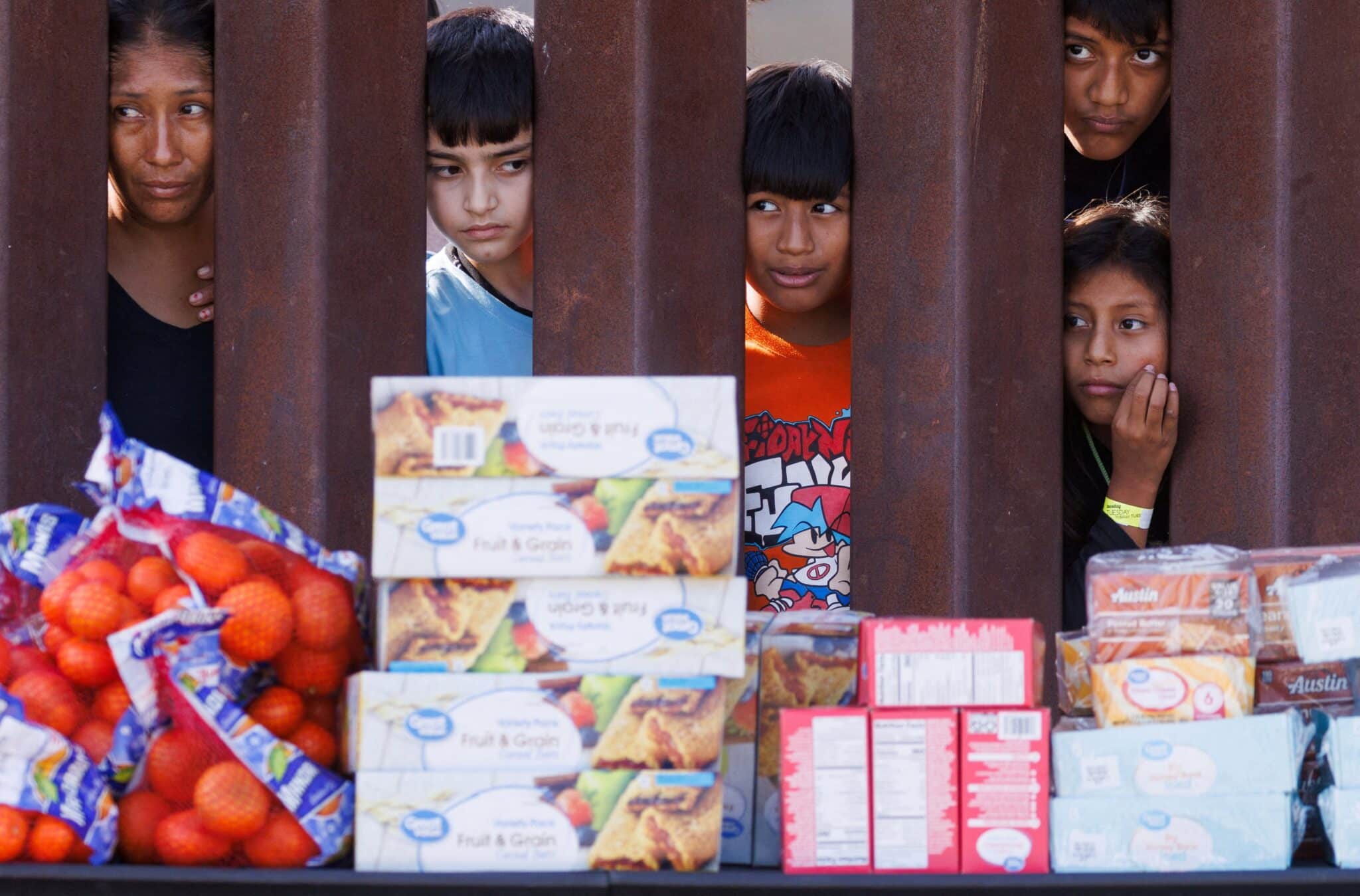 Migrants look through the border fence Sept.12, 2023, toward food brought by aid workers after gathering between the primary and secondary border fences at the U.S.-Mexico border to wait for processing by U.S immigration officials in San Diego.(OSV News photo/Mike Blake, Reuters)