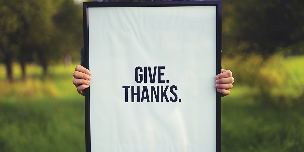 Person holding give thanks sign
