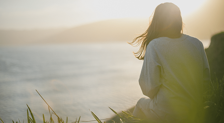 Woman sitting by water, peaceful