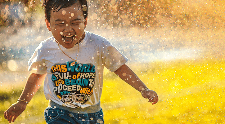 Child laughing while running through water.
