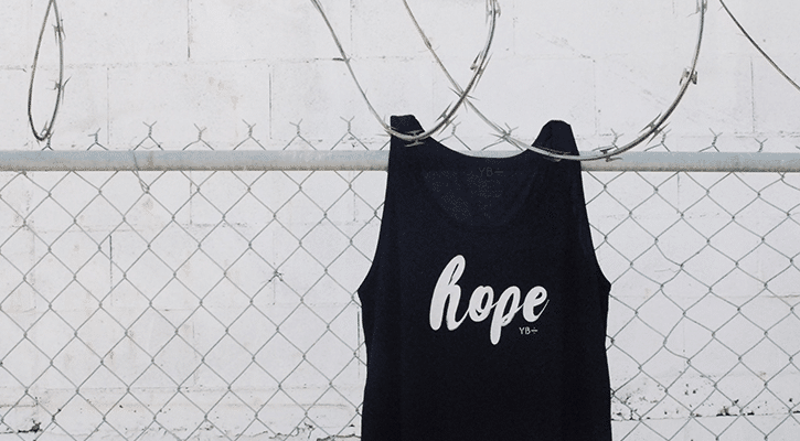 shirt with the word hope printed on it hanging on a fence.