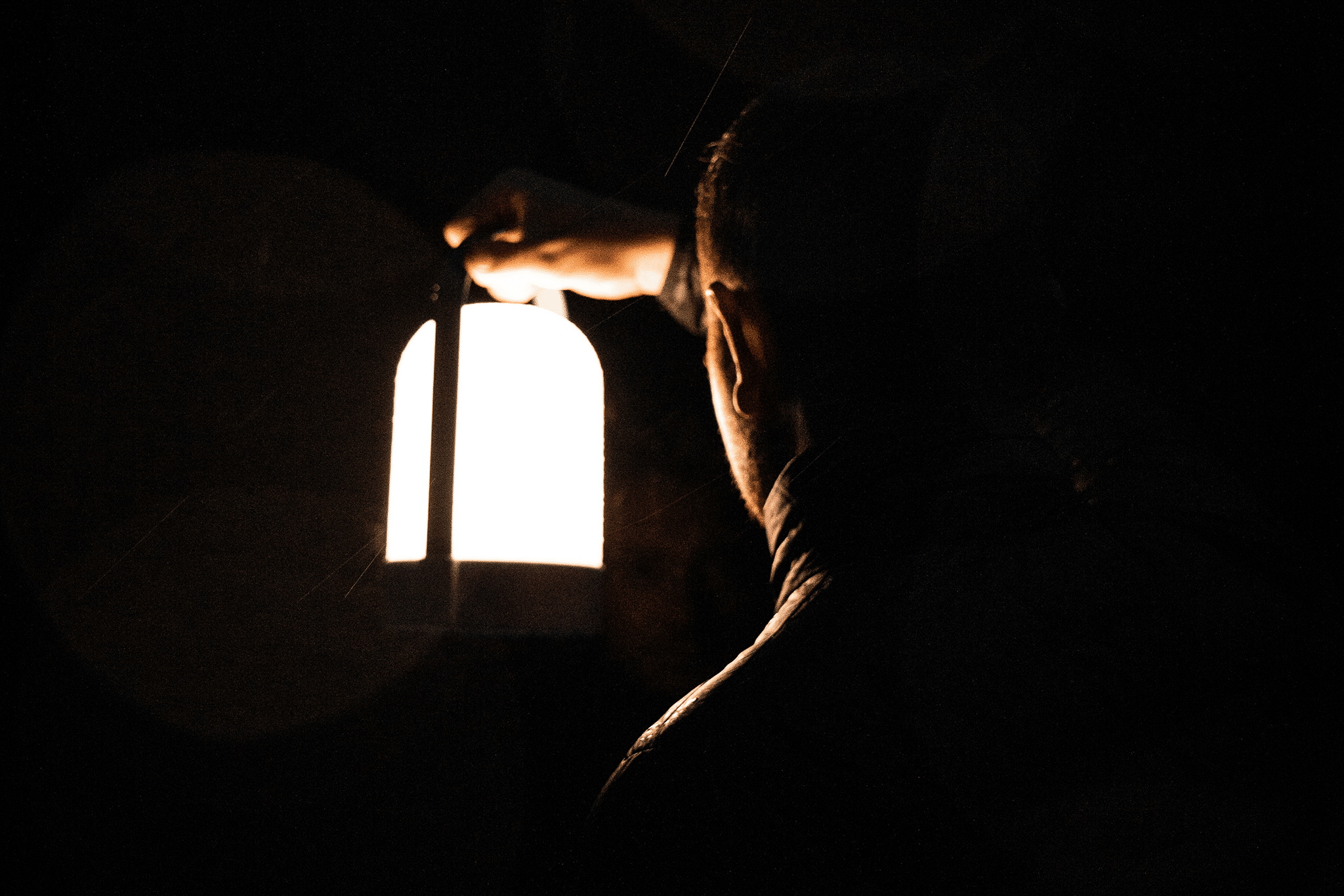 Person holding lantern in the darkness