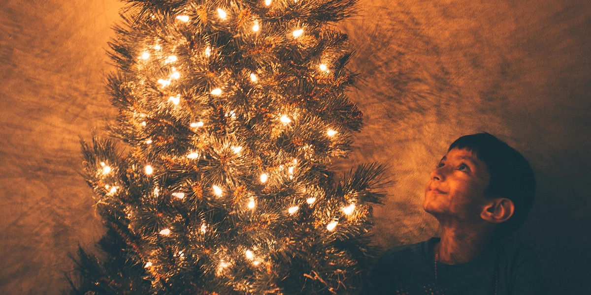 Boy sitting by Christmas Tree