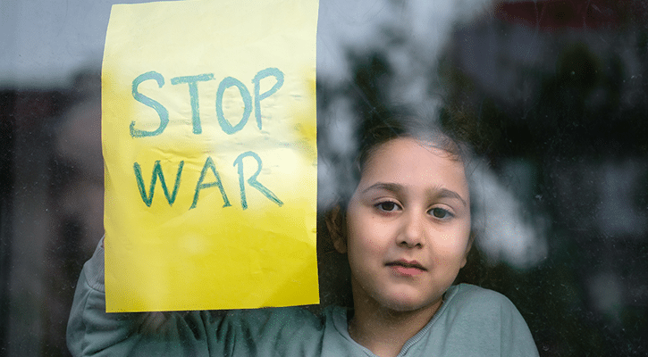 child looking out the window next to a peace poster