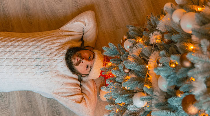 man resting under Christmas tree