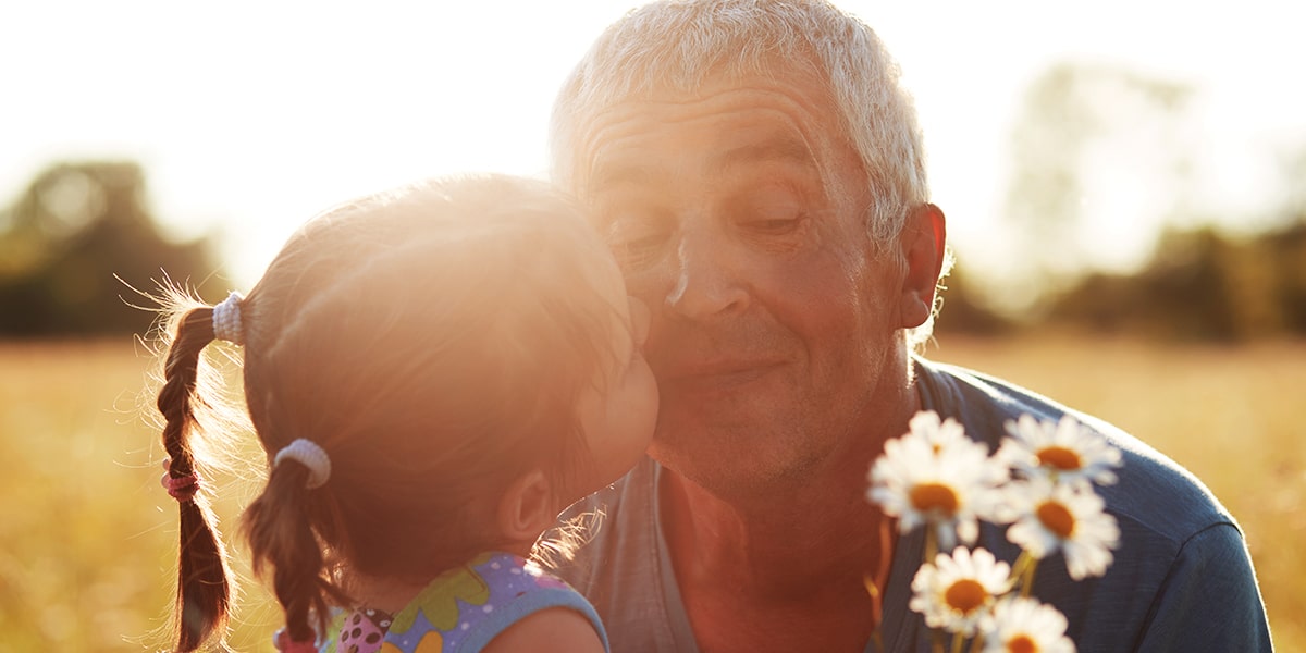 granddaughter kissing grandfather on the cheek.