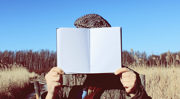 man hiding behind book