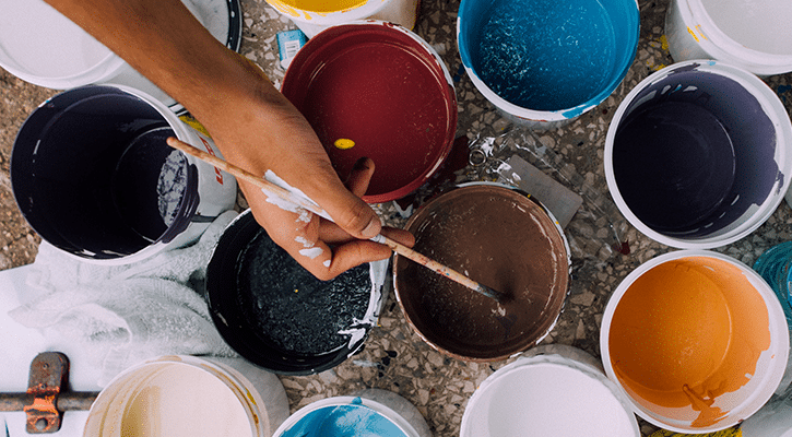 painter dipping paint brush in paint