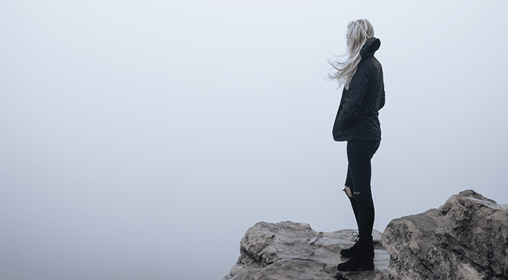 woman on a cliff surrounded by fog