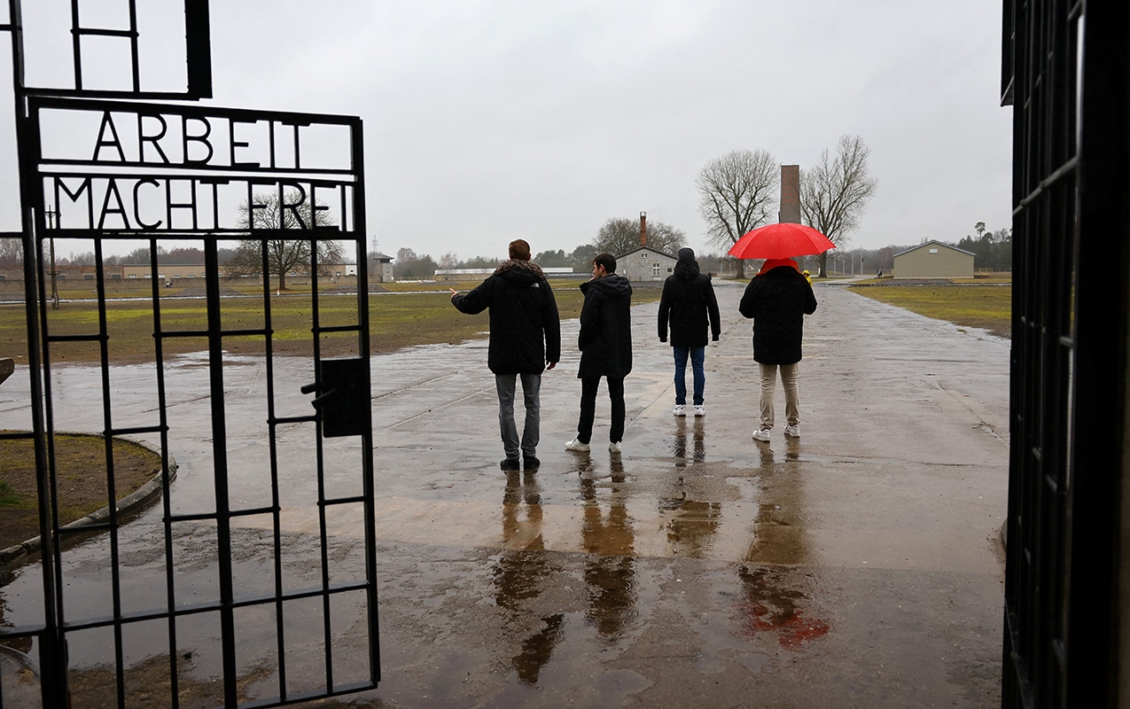 Visitors walk beside the words "Arbeit macht frei" ("Work makes one free" in German) as they pass the main entrance gate of the former Nazi concentration camp Sachsenhausen in Oranienburg, Germany, Jan. 26, 2024, the eve of Holocaust Remembrance Day. (OSV News photo/Fabrizio Bensch, Reuters)