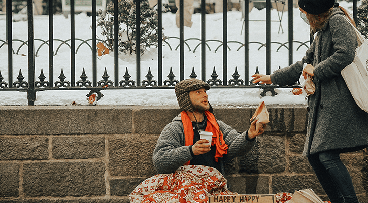 woman sharing food with a homeless man