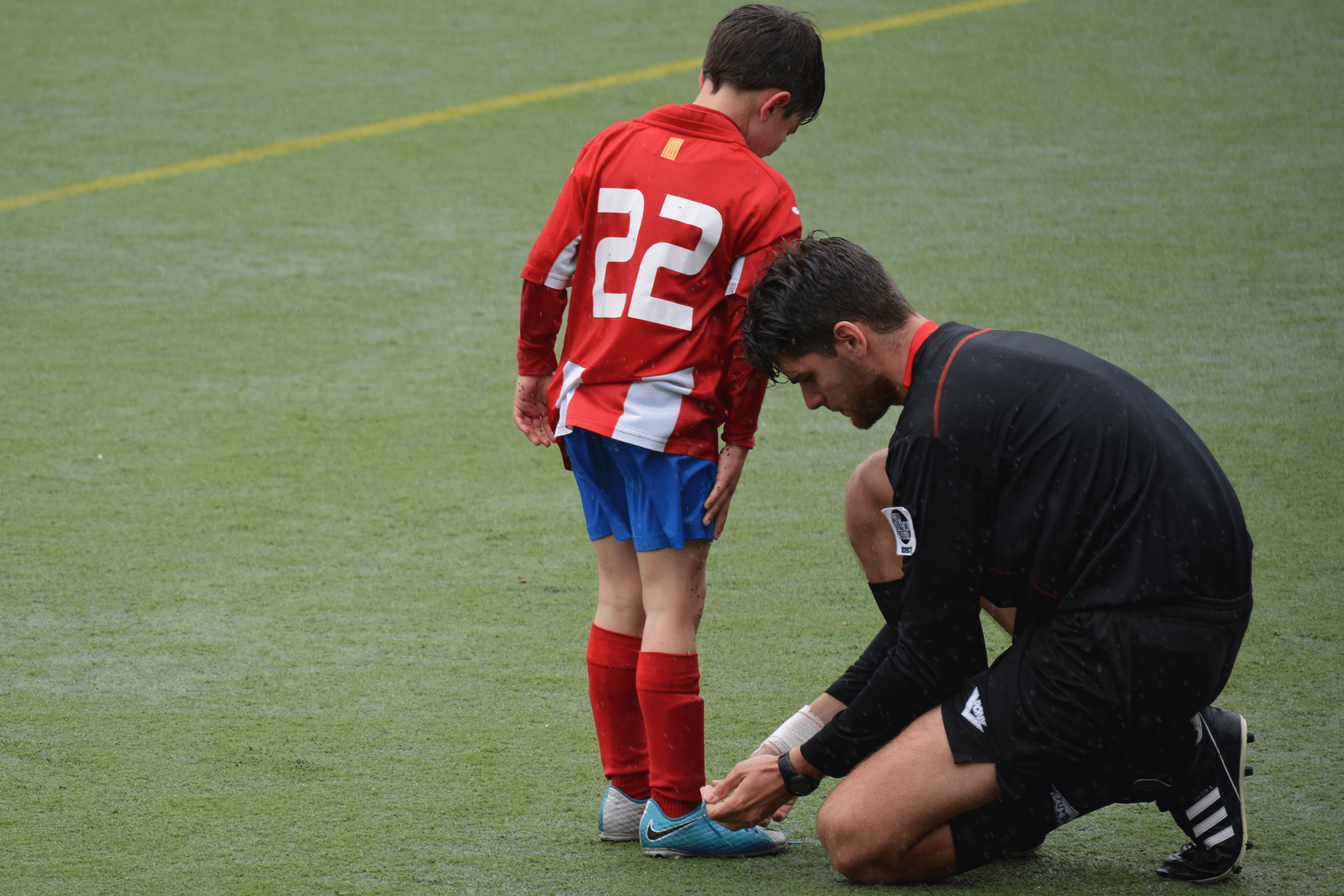 adult helping child tying his shoes