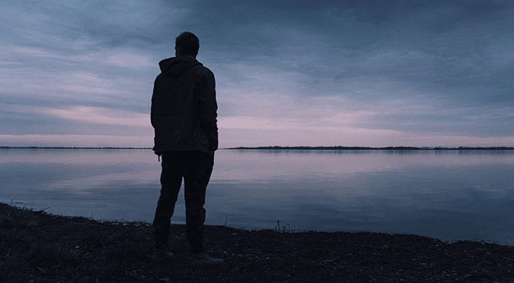 Man standing by the water at night