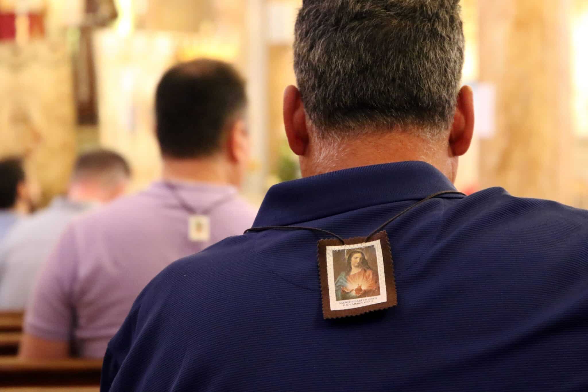Men are seen wearing scapulars during a Mass July 16 marking the feast of Our Lady of Mount Carmel at the Pontifical Shrine of Our Lady of Mount Carmel in East Harlem, N.Y. Founded in 1884 to serve Italian immigrants, the parish now ministers to a congregation comprised primarily of people of Haitian and Latino ancestry. (CNS photo/Gregory A. Shemitz)