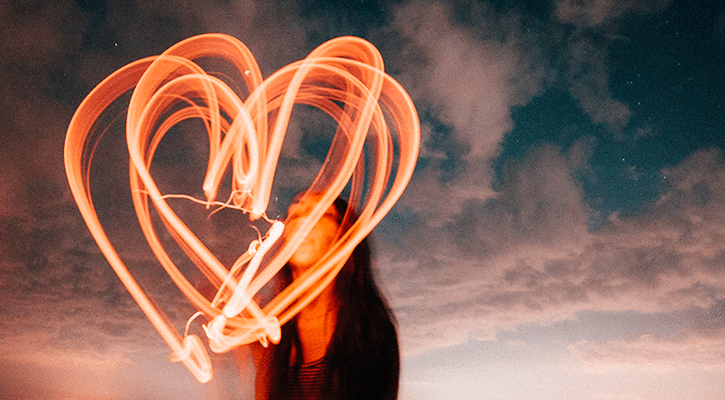 woman drawing a heart in the sky at night