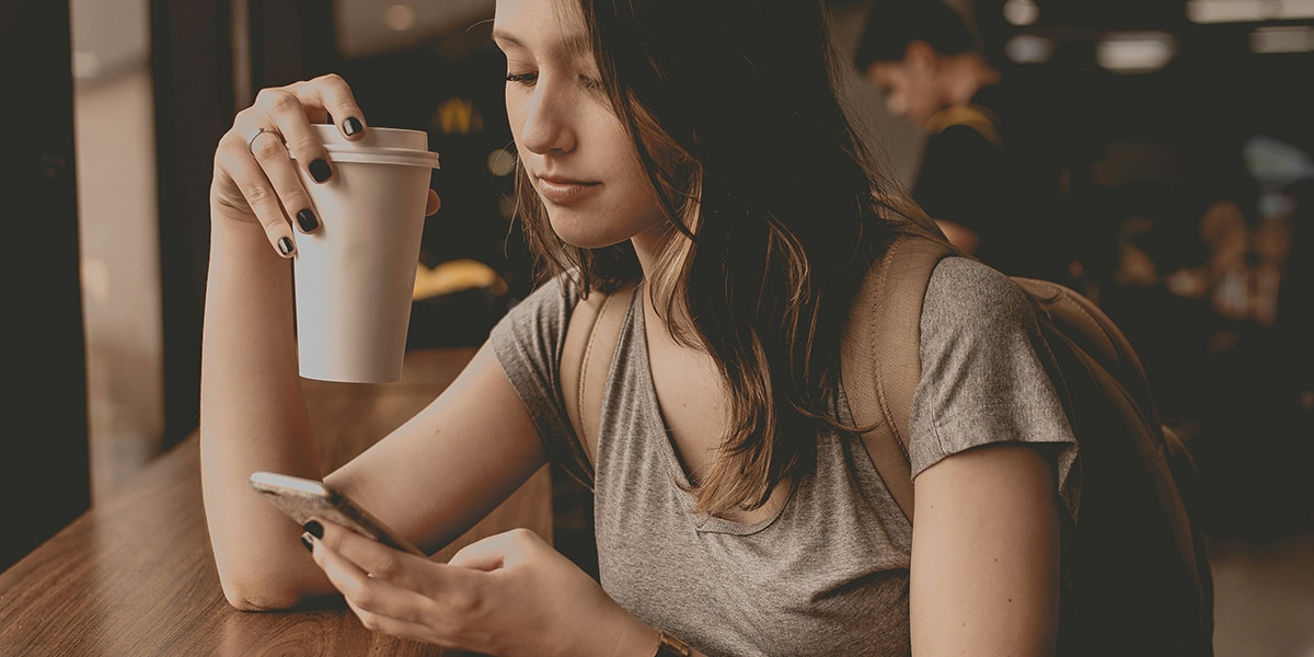 young woman drinking coffee and checking her phone
