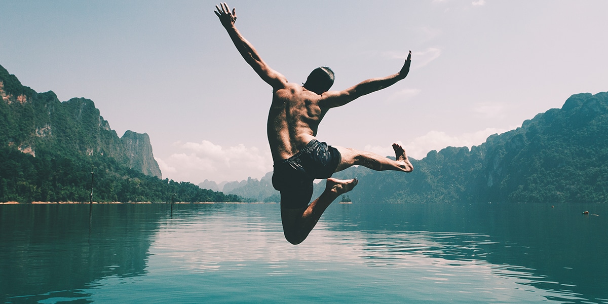 boy jumping of dock into lake