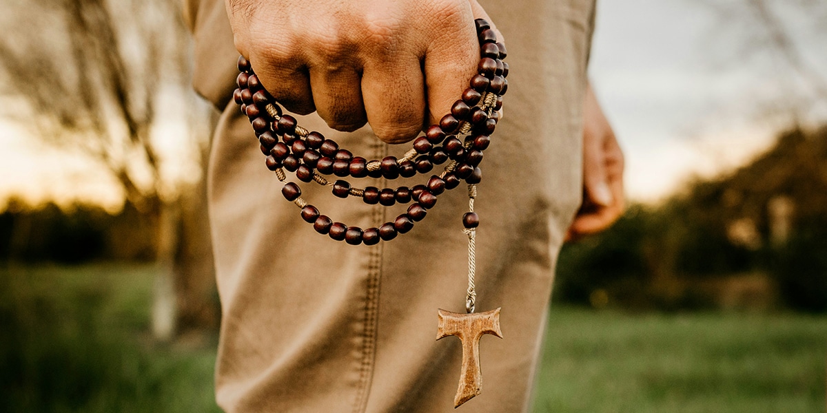 man holding rosary with cross