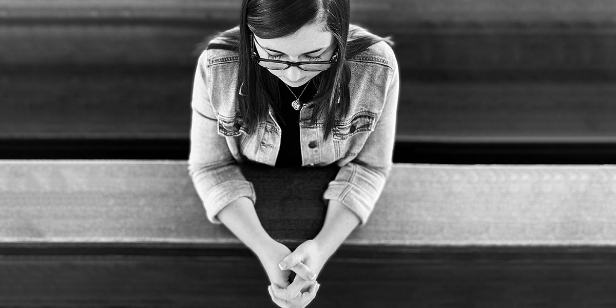 young woman is praying in pew