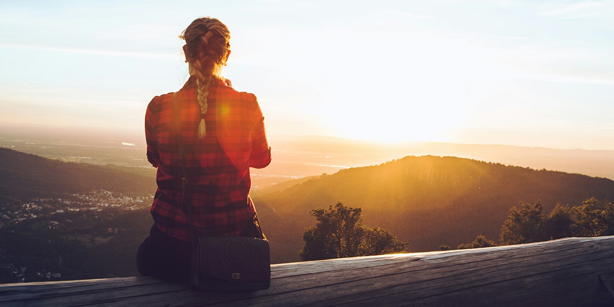 woman sitting quietly overlooking a valley