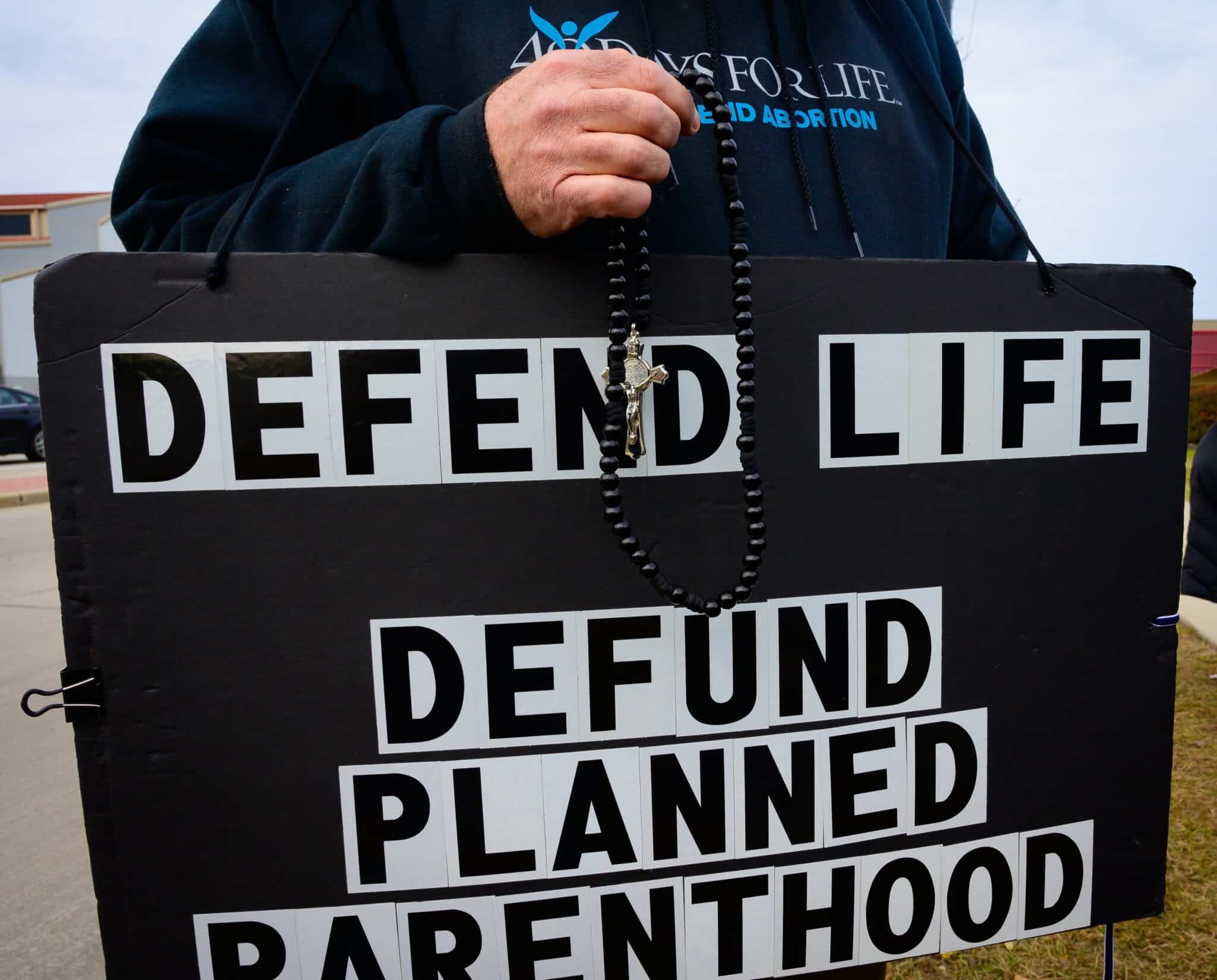 person-holding-sign-saying-defend-life-defund-planned-parenthood