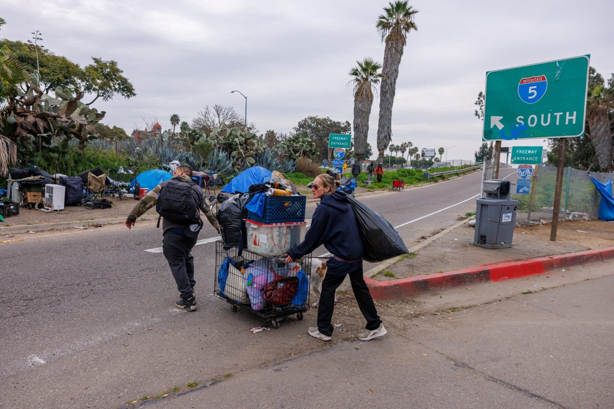 A homeless couple moves their belongings to the side of a freeway on land under state jurisdiction, after being evicted from a downtown location on the side of a city street, in San Diego, Feb. 26, 2024. (OSV News photo/Mike Blake, Reuters)