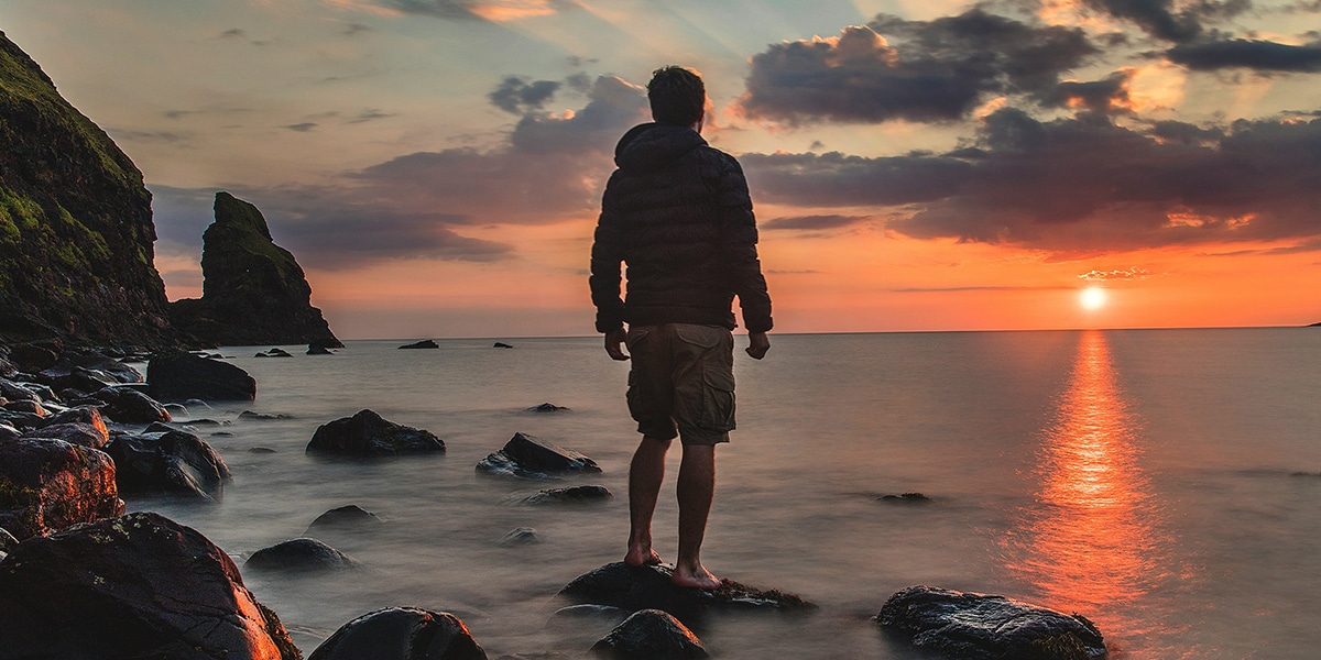 young man watching a sunset by the ocean.