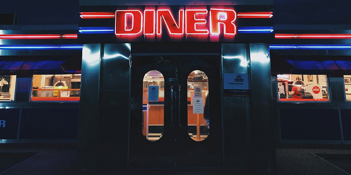 A restaurant with a diner neon light at night.