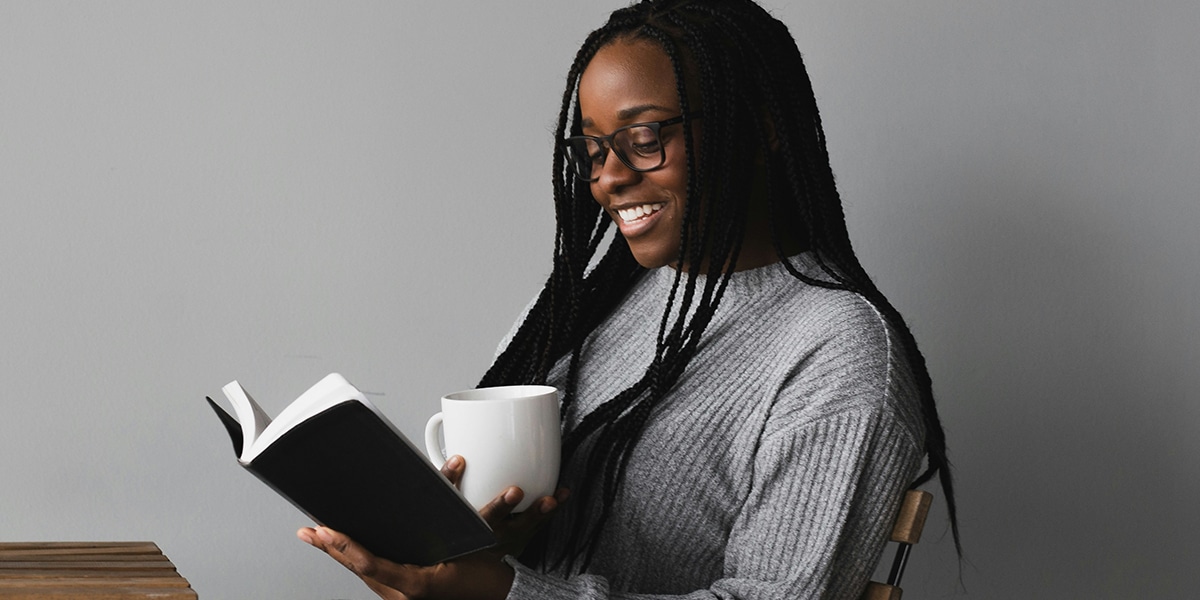 Young woman enjoys reading a book while drinking coffee