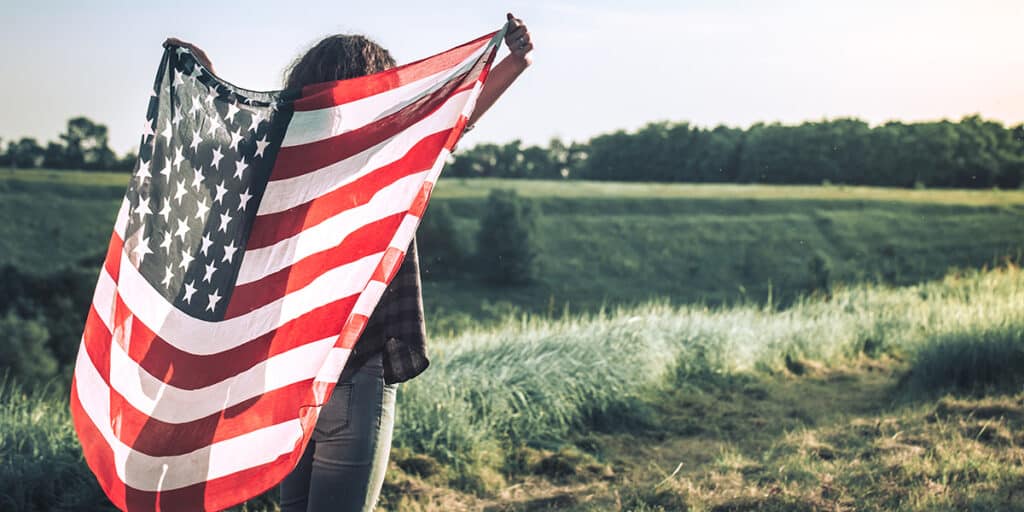 woman wrapped in an American flag in a field