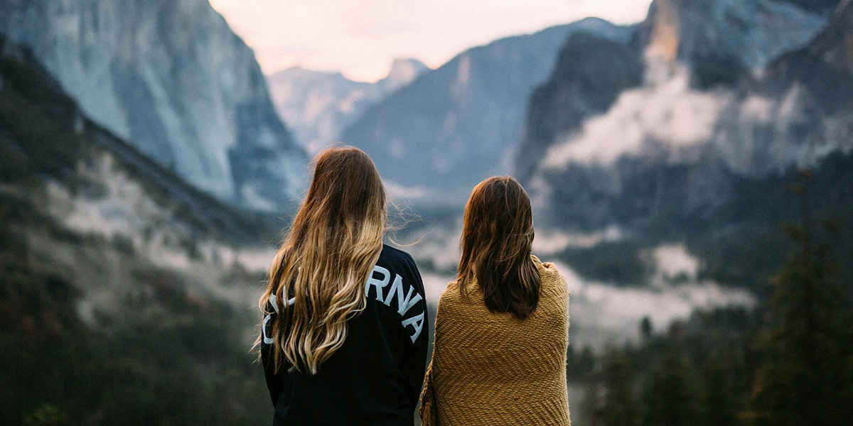 two women enjoying their friendship while standing in nature.