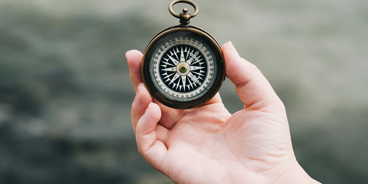 hand holding a compass searching for direction