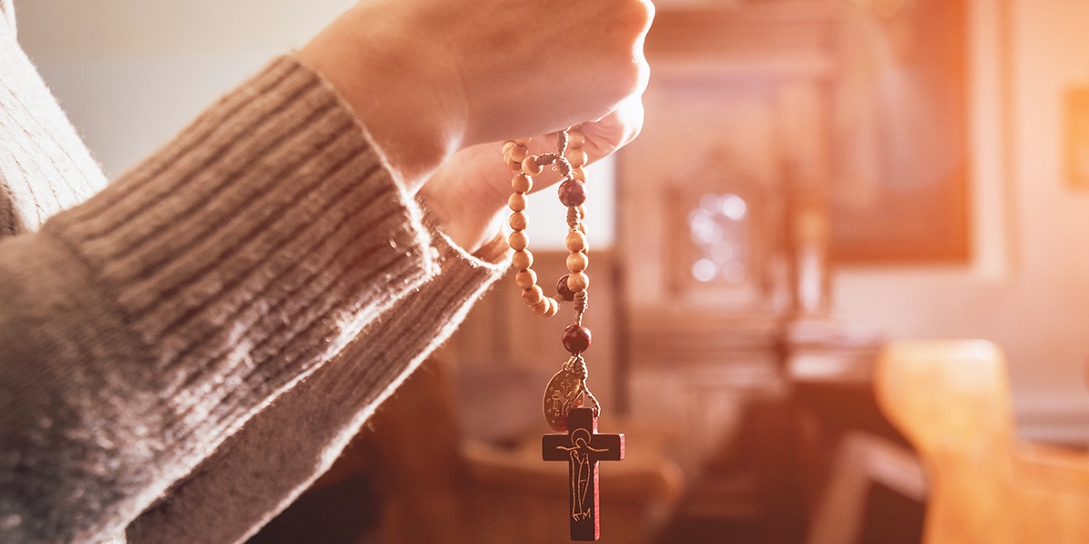 person praying with rosary in a church
