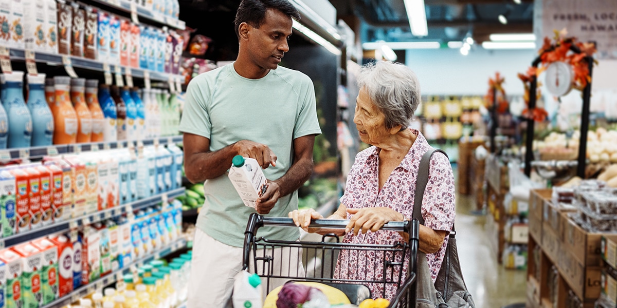 Young man helping older woman at grocery store
