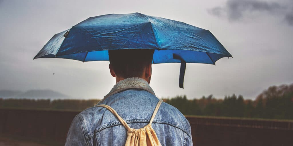 man walking with a blue umbrella during rain
