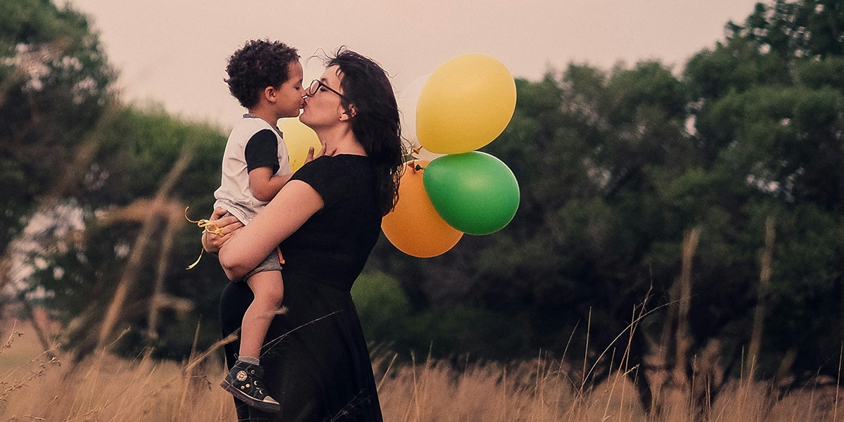 mother kissing her child while holding him in her arms.