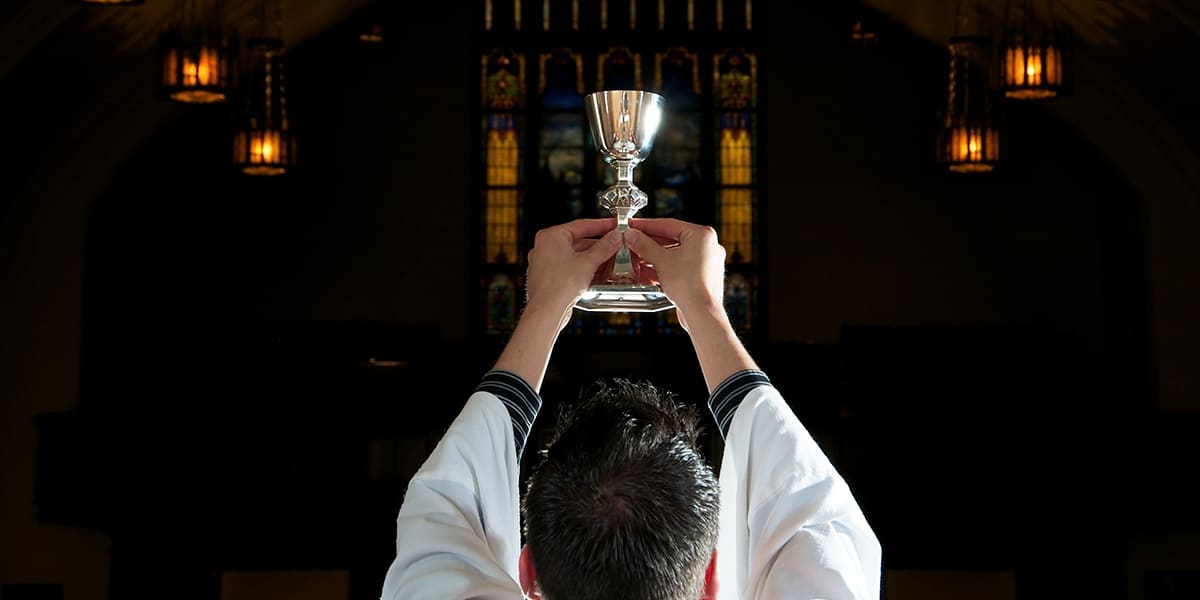 priest holding up a chalice with both hands