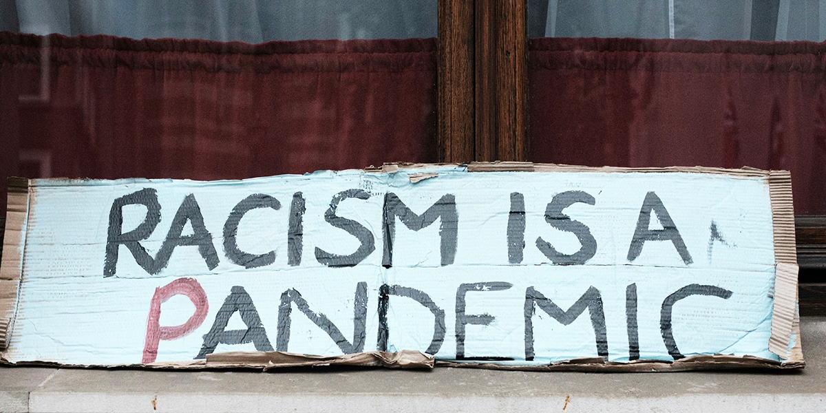 sign that says racism is a pandemic