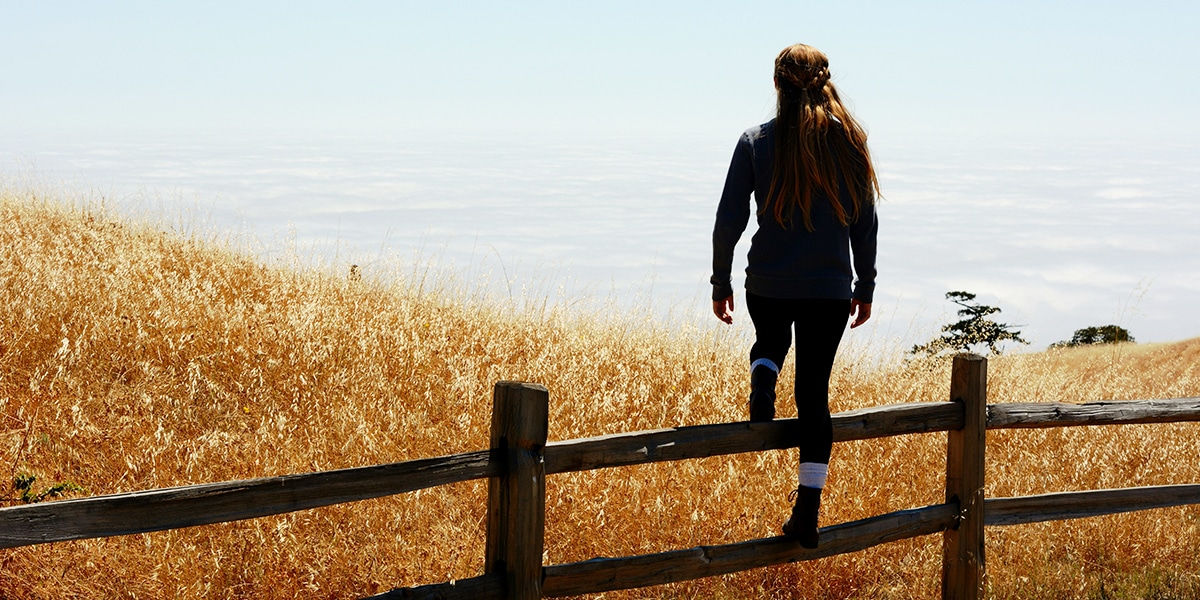 woman climbing over wood fence.