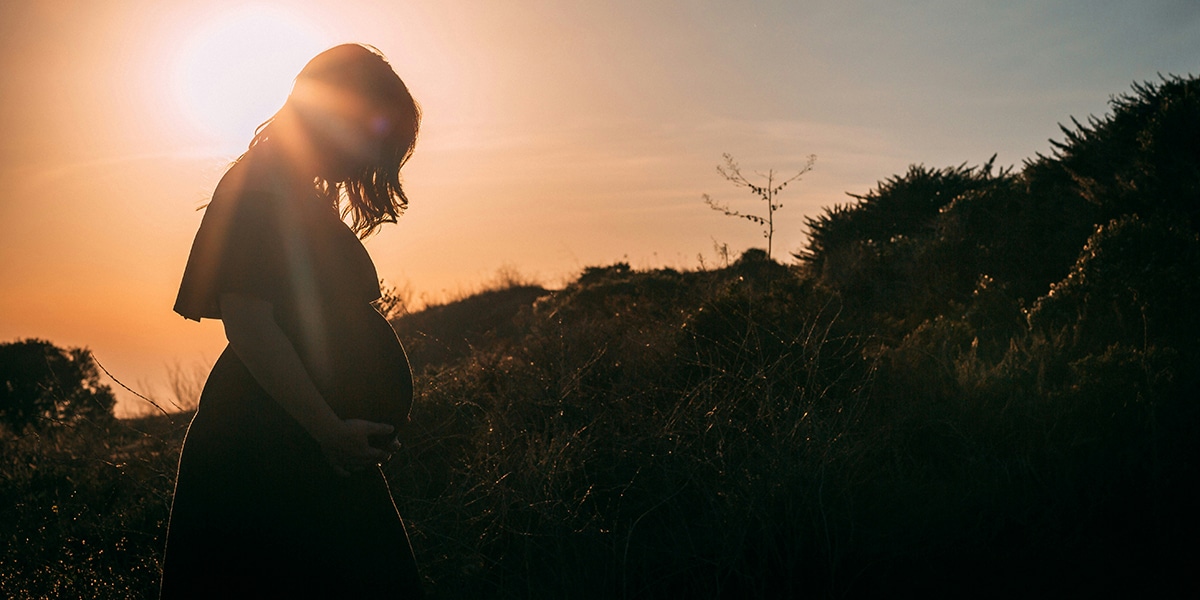 Pregnant woman walking outside at sunrise